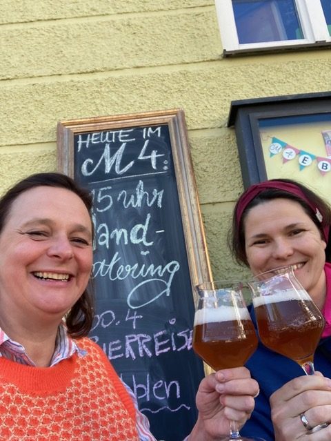 Karin und Tanja stoßen mit einem besonderen Bier im Schanigarten an